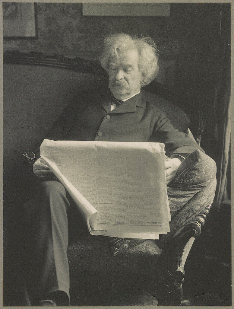 Mark Twain sitting and reading a newspaper (circa 1902).  Courtesy U.S. Library of Congress.