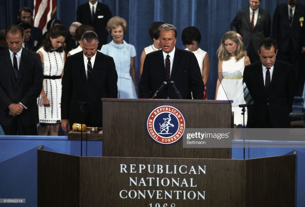 Reverend Billy Graham delivers a prayer, Spiro Theodore Agnew to his right, Richard Milhous Nixon to his left, 1968 Republican National Convention, Miami Beach Convention Center, Miami Beach, Florida, Thursday, 8 August 1968. (Photo Bettmann collection via Getty Images.)