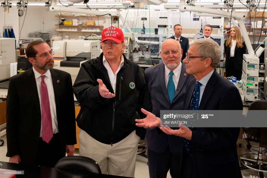 FOREGROUND (FROM LEFT TO RIGHT):
ALEX MICHAEL AZAR II, DONALD JOHN TRUMP, ROBERT RAY REDFIELD, JR., AND STEVE MONROE.
BACKGROUND (FROM LEFT TO RIGHT):
DOUGLAS ALLEN COLLINS, DAVID ALFRED PERDUE, JR., AND
KELLY LYNN LOEFFLER.
AT THE CENTERS FOR DISEASE CONTROL AND PREVENTION,
IN ATLANTA, GEORGIA, ON FRIDAY, 6 MARCH 2020.
(PHOTO BY JIM WATSON/AFP VIA GETTY IMAGES.)